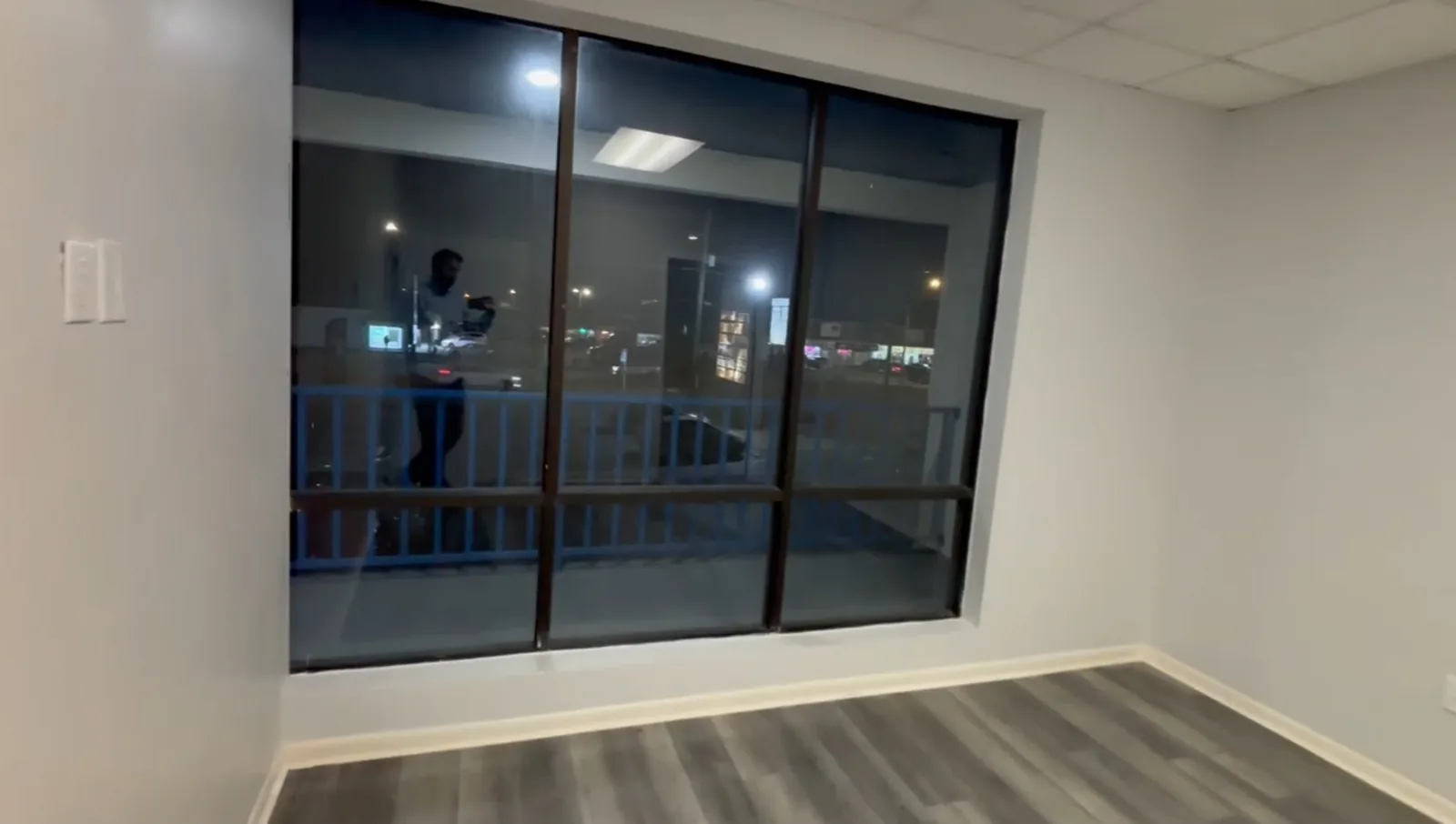 A finished commercial office suite with a fresh gray laminate floor, clean baseboards and a large storefront window, cleaned and ready for move-in