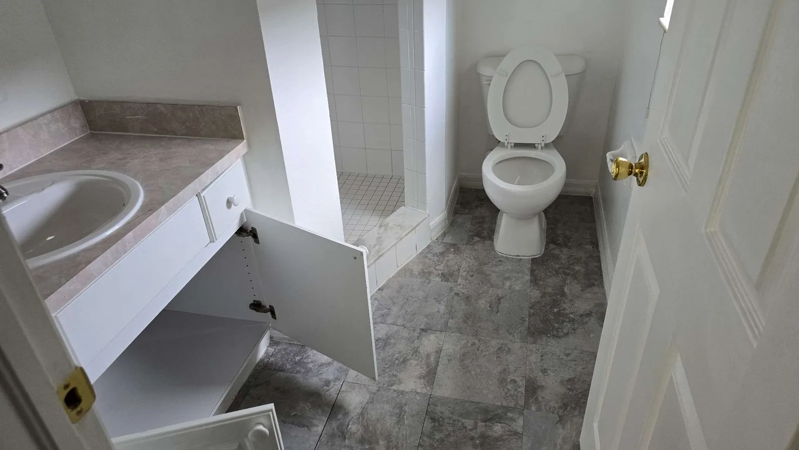 A rehabbed bathroom with a clean walk-in shower, tub and vanity after the property rehabilitation